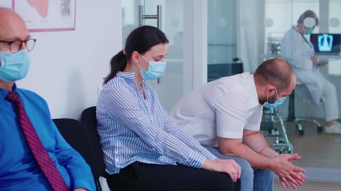 Worried young couple wearing face mask against infection with coronavirus while waiting news from doctor. Wife crying from unfavorable news during covid-19.