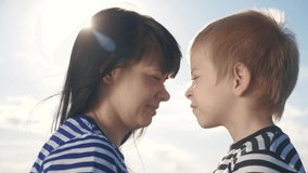 son and mom cute video concert mother's lifestyle day. teamwork happy family boy kisses mother on the cheek touches his nose. parent takes care of the child. kid and adult woman mom in the sunlight at