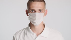 Attractive casual guy taking off medical mask happily smiling on camera isolated. Safety first concept