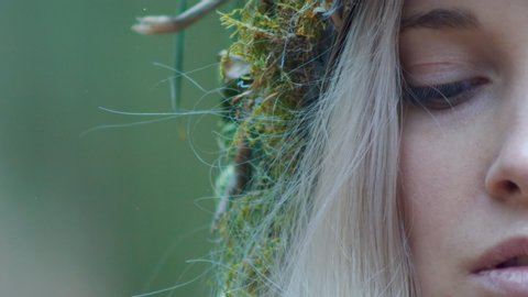 Beautiful girl in earthy crown looks up into lens, space for titles