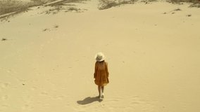 Young woman walking at desert on sunny day. Drone video recording