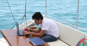 Young boy on yacht deck using laptop computer