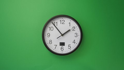 Single white office clock hanging on green background, timelapse