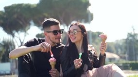 Portrait young couple of tourists sitting in sunglasses in the park on the lawn. Eat ice cream cones. Cheerful friends feasting on delicious ice cream on an urban background. Rome, Italy - Powered by Shutterstock - Get 15% off with code: PIKWIZARD15