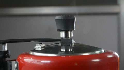 Closeup view of steam releasing from a pressure cooker in a kitchen.