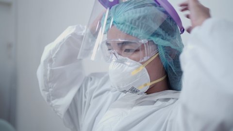 Asian female nurse wearing white ppe suit, medical protective suit, protective glasses, n95 mask and face shield pandemic covid-19 corona virus, in the medical clinic, infectious disease prevention