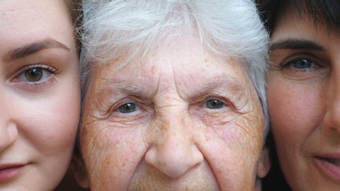 Portrait of elderly woman with her daughter and granddaughter looking into camera together. Three female faces. Slow motion Close up
