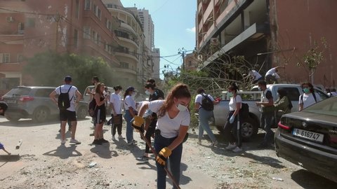 BEIRUT, LEBANON - 5 AUG 2020: Young men and women remove rubble from streets. A massive explosion caused by explosive materials destroyed the port of Beirut and damaged large parts of the city