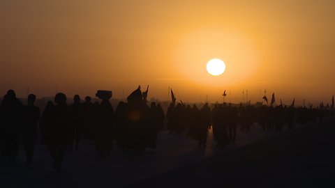 KARBALA, IRAQ - NOV 2017: Silhouette of crowd of pilgrims walking in Arbaeen pilgrimage at sunrise. Every year, millions of Shiite muslims come from all over the world to Karbala to walk Arbaeen