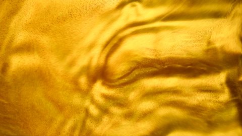 Liquid gold abstract background. Flowing Golden abstract backdrop. Beautiful metallic yellow texture. old metallic paint with a brush close-up. Liquid gold Art Wallpaper. 4K UHD slow motion. 