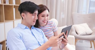asian couple looking some information on the internet together with digital tablet at home happily