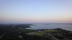 4K drone aerial view of beautiful vacation spot with boats, trees, water sports, blue skies, and nature.  Magic hour sunset at dusk with blue, orange, and pink gradient sky is an inspirational sight.