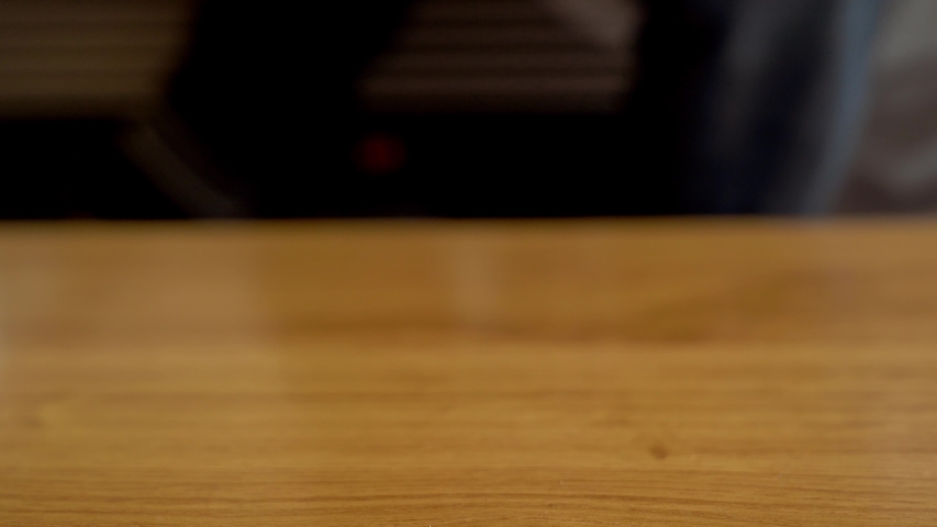 Cropped unrecognizable person in apron putting muffin tray with delicious baked muffins in paper case on top of wooden table