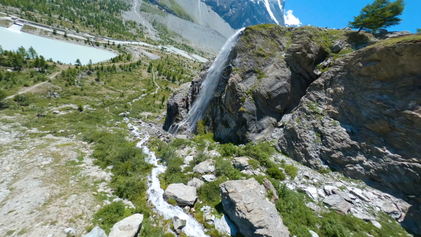 Drone Circling Fast Around A Nice Waterfall In Zermatt, Switzerland. Matterhorn Summit Seen In The Background - FPV drone shot Royalty-Free Stock Footage #1057067873