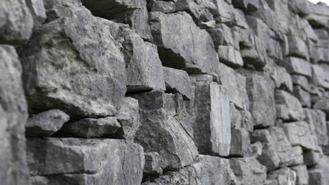 Ancient rock wall ruins made of grey stacked stones - slow motion close up tracking shot stone texture