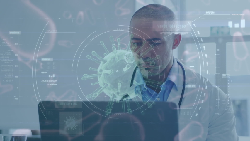 Animation of macro Covid-19 cell floating over a view of mixed-race male health care worker working with his laptop in hospital. Coronavirus Covid-19 pandemic concept digital composite | Shutterstock HD Video #1057077677