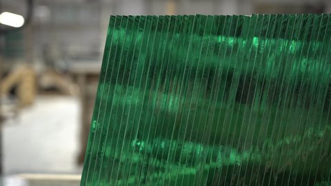 Stack of glass sheets cut to exact same size stacked in a row in glass factory. Sheets of factory manufactured tempered clear green glass. Glass cutting industry.