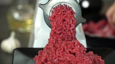 Close up of preparation of minced fresh beef through electric meat grinder. Meat cooking concept. Food background
