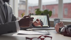 Midsection shot of afro-american entrepreneur in formalwear signing contract and giving handshake to male business partner while sitting together at office table - Powered by Shutterstock - Get 15% off with code: PIKWIZARD15