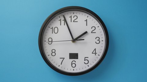 White office clock hanging on a blue color wall.