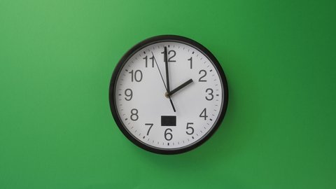 Single white office clock hanging on green background