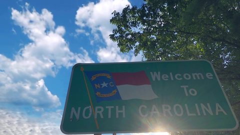 Time lapse clouds over state sing of Welcome to North Carolina. High quality 4k footage. State line sign for North Carolina entrance.