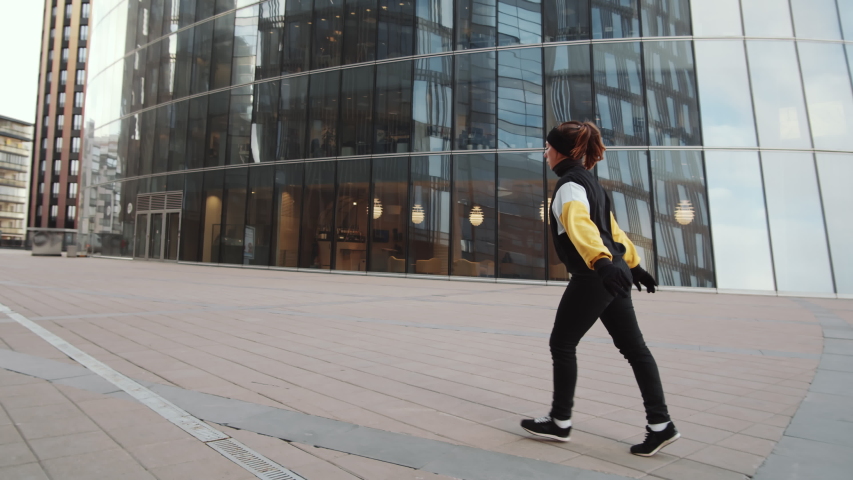 Young sporty woman performing aerial cartwheel while practicing parkour outdoors in front of modern glass building in the city Royalty-Free Stock Footage #1057089026