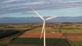Aerial top view wind turbine, moving above the white modern construction on countryside green field. Windmill Wind power technology - Aerial drone view on Energy Production.