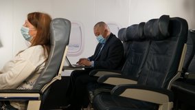4K: Female Caucasian Airplane Passenger applying Hand Sanitiser and wearing a Face mask on plane journey. Air Travel. Stock Video Clip Footage