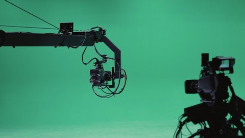 Film crew and equipment in green studio shooting video. Filmmaking industry.