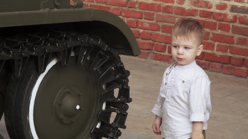 A boy plays on the site with military equipment