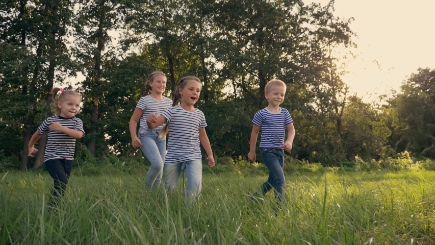 Happy family of children playing with a ball in park. Happy kid are run. Children run after ball in  park. Happy family of children at sunset in park, having fun playing with a ball. Kid dream team. Royalty-Free Stock Footage #1057108196