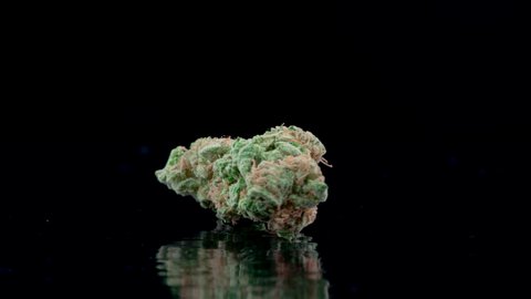 Close up of rotating medical marijuana bud on black reflecting background shot in 4k super slow motion