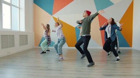 Group of dancers man and women are dancing hip-hop in modern dancehall indoors moving bodies enjoying practice. People and leisure time activities concept.