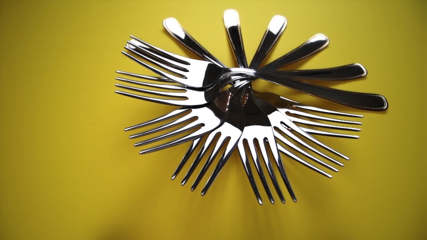 composition with silver forks laid out in circle on yellow