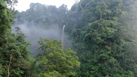 Camera is flying above waterfall in eastern tropical forrest. Fast shooting first. Drone aerial.