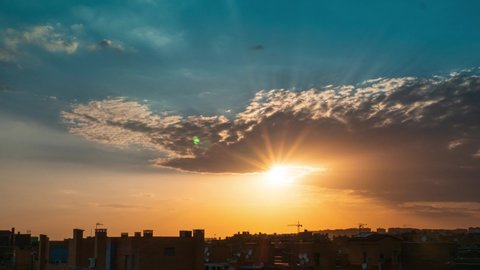 Timelapse of sunset over Vallecas city with few clouds in the sky and orange teal tones. 