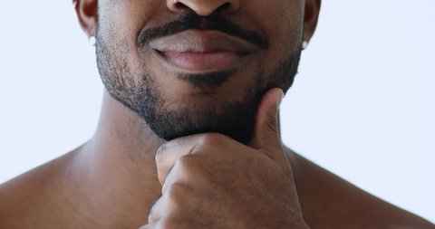 Close up young african american man touching groomed beard, satisfied with shaving barbershop procedure. Happy mixed race guy advertising products or services for facial aftershave hair care.