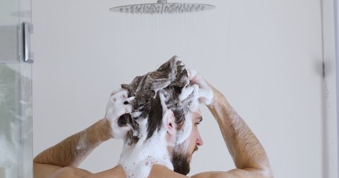 Back rear close up view young naked european man cleaning sculp with bubble shampoo. Bare man washing head with anti dandruff treatment, enjoying morning daily showering body care hygienic routine.