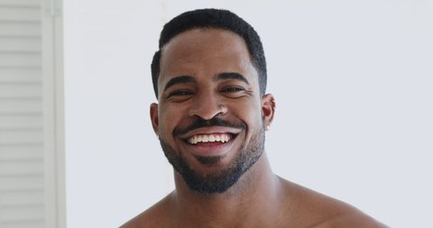 Close up head shot portrait of young smiling shirtless handsome african american man. Happy mixed race guy with toothy white smile looking at camera, satisfied with dentistry or skincare procedure.
