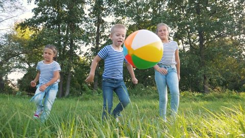 Happy family of children having fun in the park. Happy kids are running. Children run for a colorful ball in the park. Children at sunset in the park have fun playing with a ball. team dream of kids.