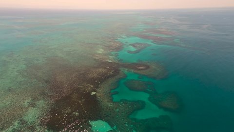 Great Barrier Reef Blue Sea view. Beautiful aqua & turquoise waters, with coral reef patterns in the ocean. View from helicopter, on vacation. Marine life, global warming, protection, island. 4K.