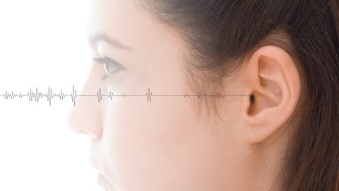 Hearing test showing ear of young woman with audio sound waves simulation technology - isolated on white loopable