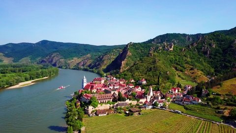 Aerial descending shot of the medieval town Durnstein on the shore of the Danube River in Austria. 