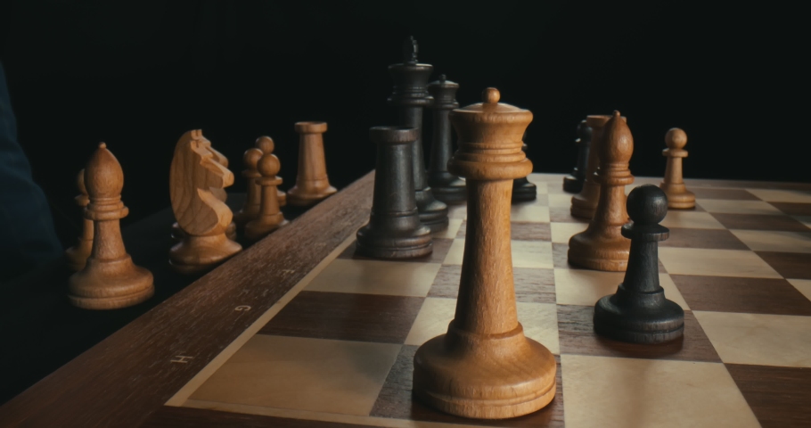 Close up of male hand moving white queen defeating black king. Checkmate. Grandmaster making strategic move and winning opponent making checkmate isolated on black background Royalty-Free Stock Footage #1057132559