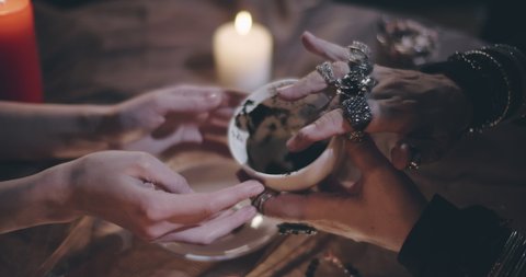 Close up of customer and fortune teller hands holding empty mug with coffee grounds foreseeing future. Woman visiting witch for fortune prediction