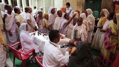 VRINDAVAN, INDIA - JUNE 14, 2015: A doctor conducts a medical examination of older women outdoors in central India.