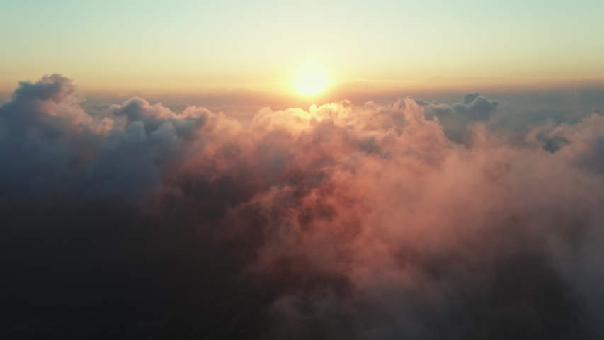 Moving white clouds blue sky scenic aerial view sunset. Drone flies high back in blue sky through fluffy clouds in evening at golden sun summer. Sun is hidden behind clouds at fog. Relax. Nature Royalty-Free Stock Footage #1057134227