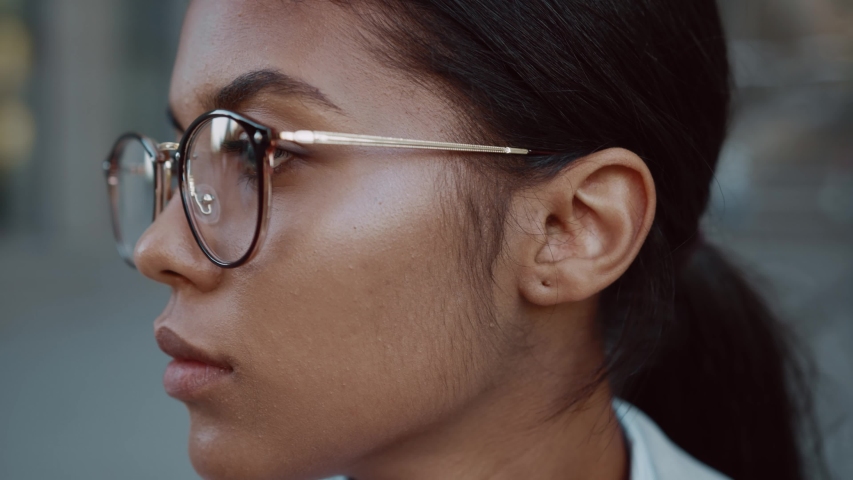 Close up face mixed race business woman in glasses standing look at camera serious outdoor in jacket posing at modern street success stylish exterior slow motion | Shutterstock HD Video #1057134506