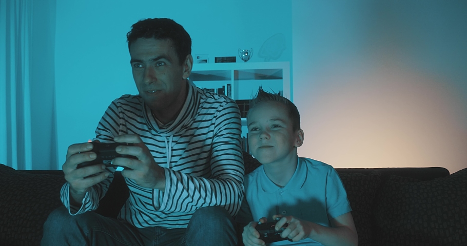 Father and son playing and winning on Video Game in Evening at Home. 4K slow motion video. | Shutterstock HD Video #1057134653